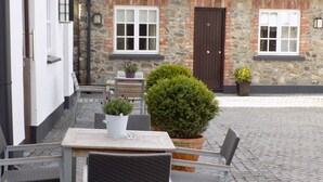 An outdoor seating area with a table and chairs, surrounded by stone walls and potted plants. - Flynns of Termonfeckin (Termonfeckin)