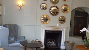 A living room with a fireplace, multiple mirrors, a sofa, and a coffee table. - Flynns of Termonfeckin (Termonfeckin)