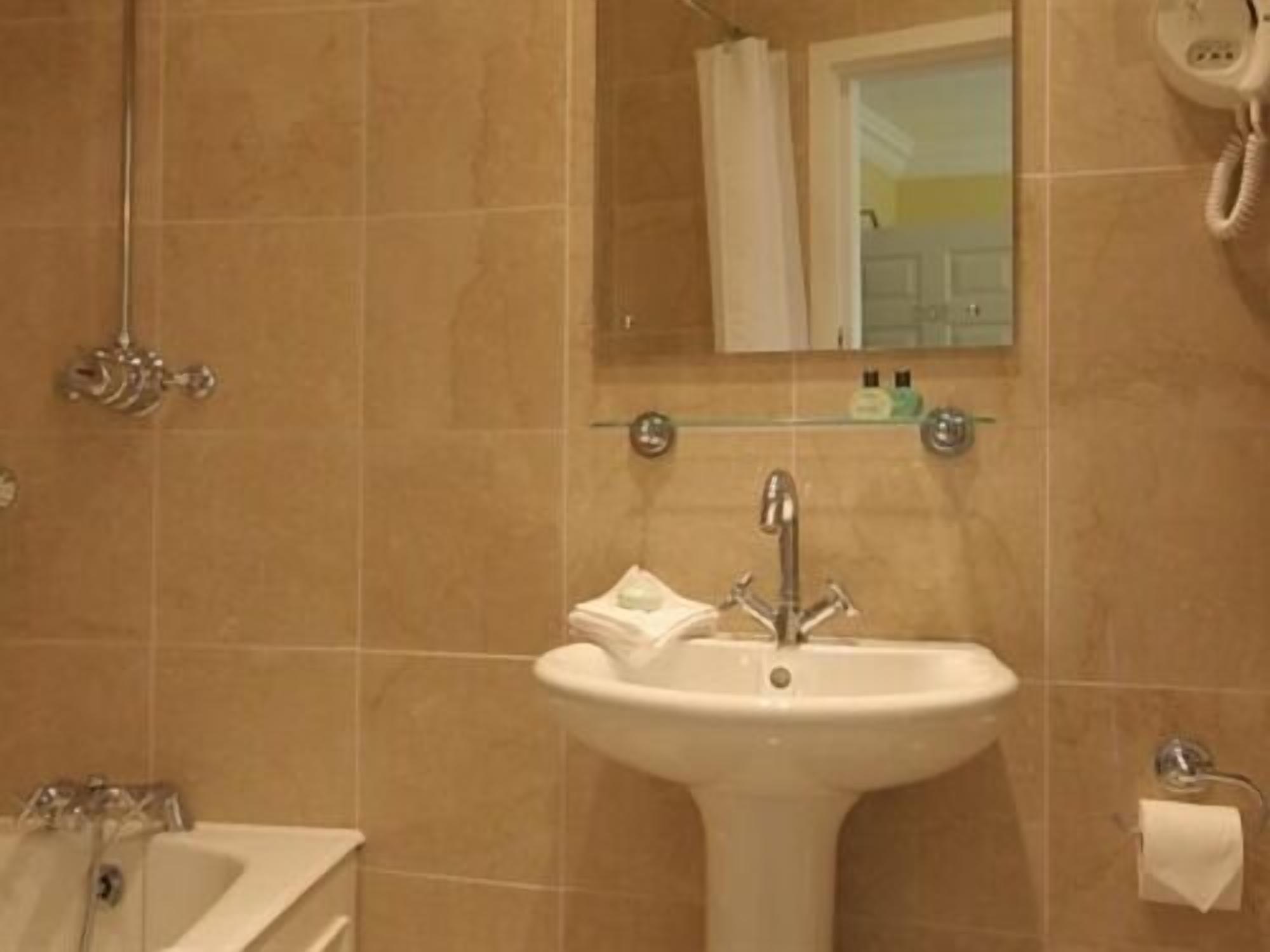 A bathroom with a sink, mirror, and a telephone.