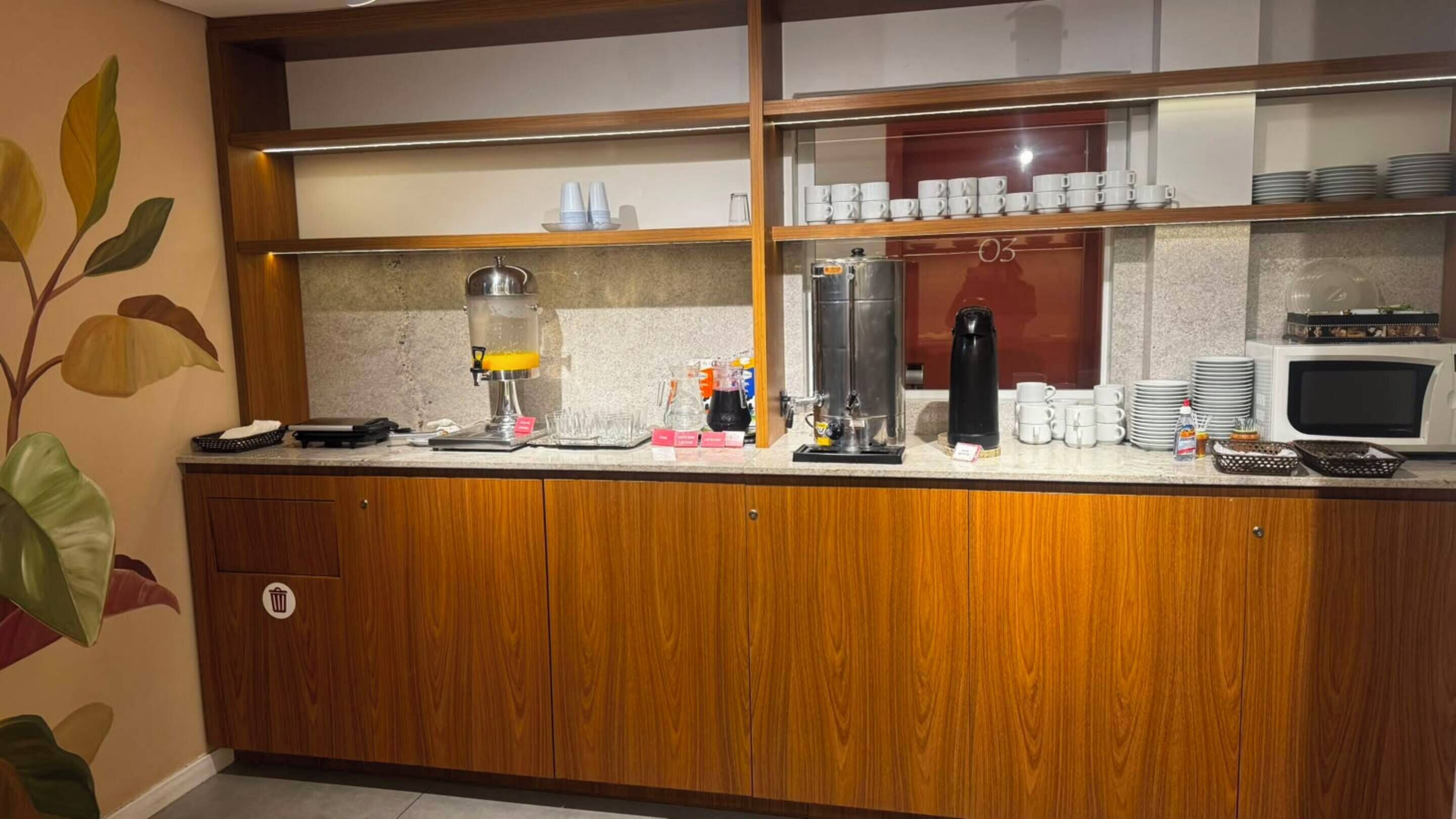 A breakfast bar with coffee machines, cups, and a microwave.