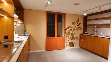 A modern kitchen with wooden cabinets, a built-in oven, and a large window with a frosted glass door.