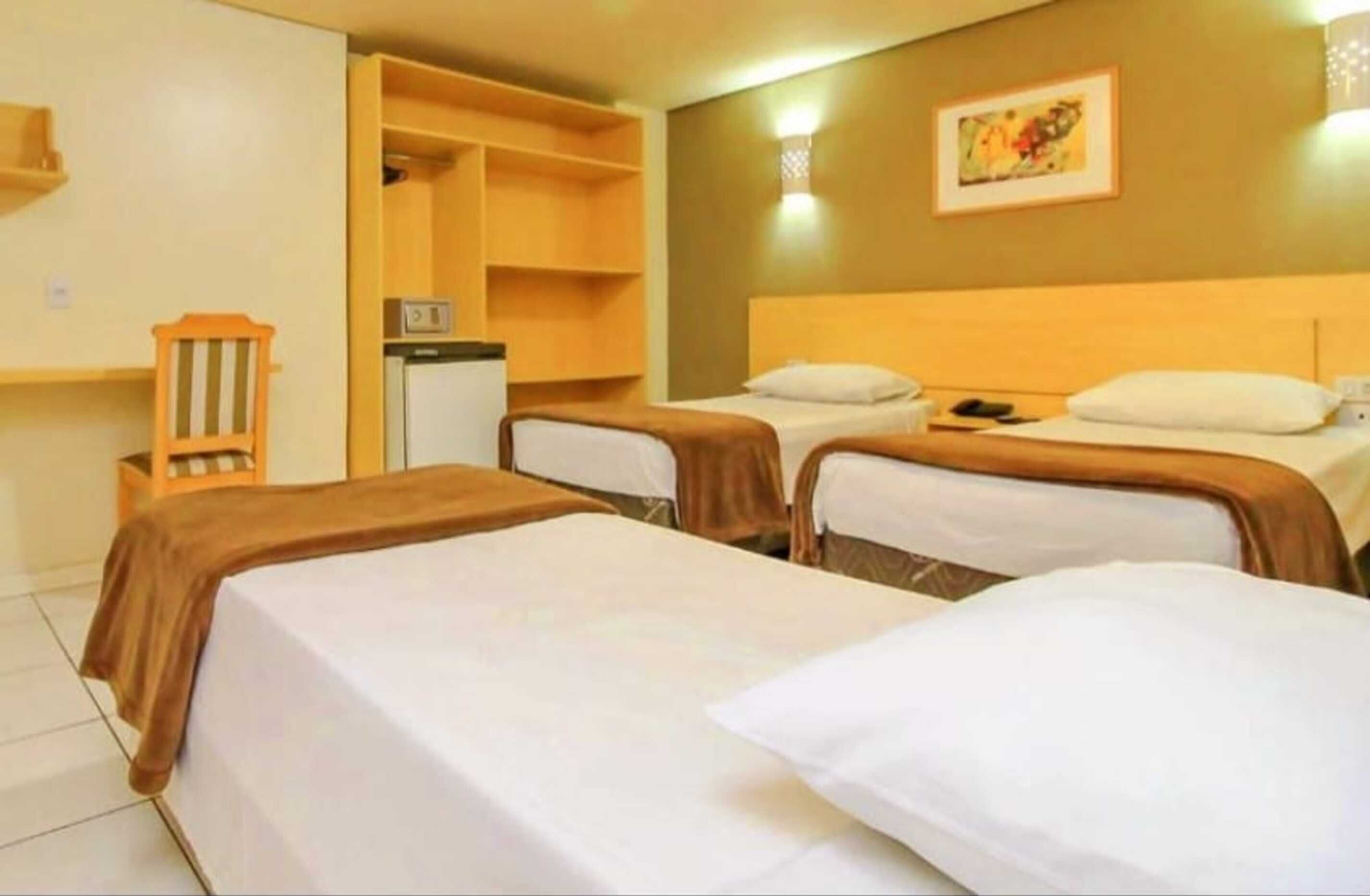 Une chambre d’hôtel avec deux lits simples, un bureau, une chaise et une armoire.