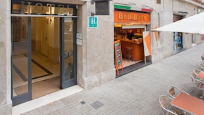 Een hotel ingang met een glazen deur, een bordje met 'Hotel Everest' en een restaurant genaamd 'BelleBuon' met terras.