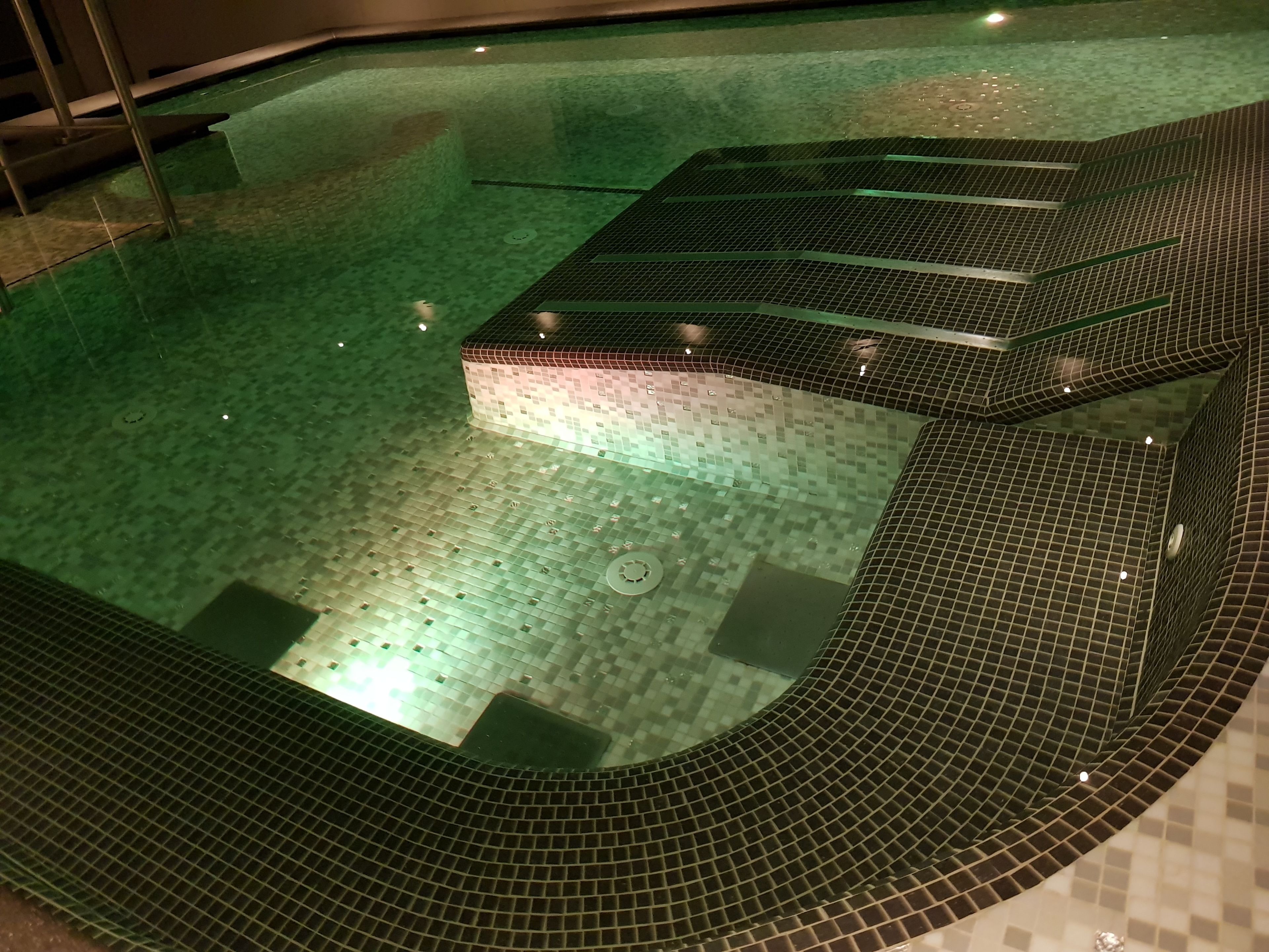 A swimming pool with a tiled floor and steps leading into the water.