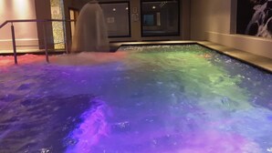 Un jacuzzi con caída de agua e iluminación de colores.