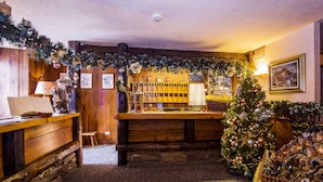 Un hall de hotel acogedor y rústico, con una recepción de madera, un árbol de Navidad y decoraciones festivas.