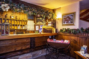 A rustic wooden bar area with a Christmas garland, a framed picture on the wall, and a vintage telephone. - Des Glaciers (Courmayeur)