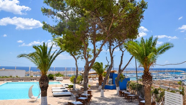 A poolside area with lounge chairs and tables, a clear view of the sea, and a beach in the background. - Approdo Boutique Hotel Leuca (Castrignano del Capo)