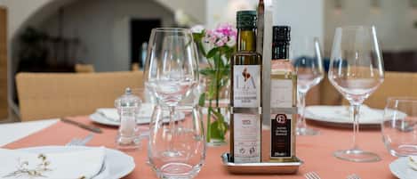 A dining table set with wine glasses, a bottle of olive oil, and a salt shaker.
