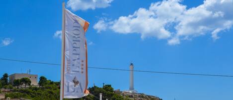 Una bandera con la inscripción "HOTEL LAPA", un faro y edificios en una colina.