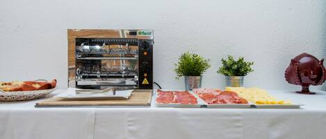 Un buffet proposant une grille, différentes sortes de viandes, du fromage et du pain.