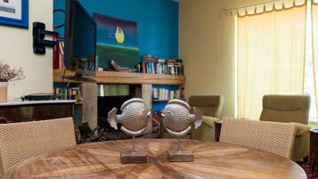 A round wooden table with two fish-shaped sculptures, surrounded by wicker chairs.