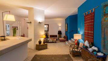 A living room with a sofa, a coffee table, and a lamp. There is a blue wall and a white wall.