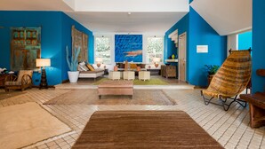 A spacious living area with a large window, a sofa set, a rattan chair, and a coffee table. - Approdo Boutique Hotel Leuca (Castrignano del Capo)