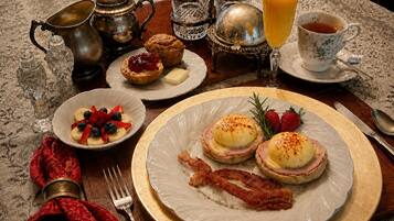 Ein Frühstückstisch mit Eggs Benedict, einem Muffin und einer Obstschale.