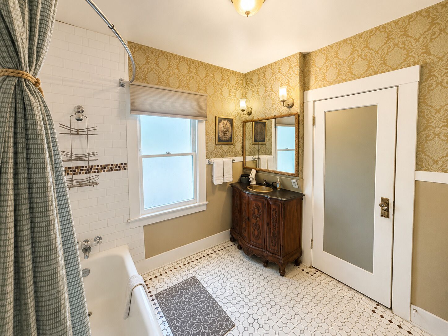 A bathroom with a bathtub, a vanity with a mirror, a shower, and patterned walls.