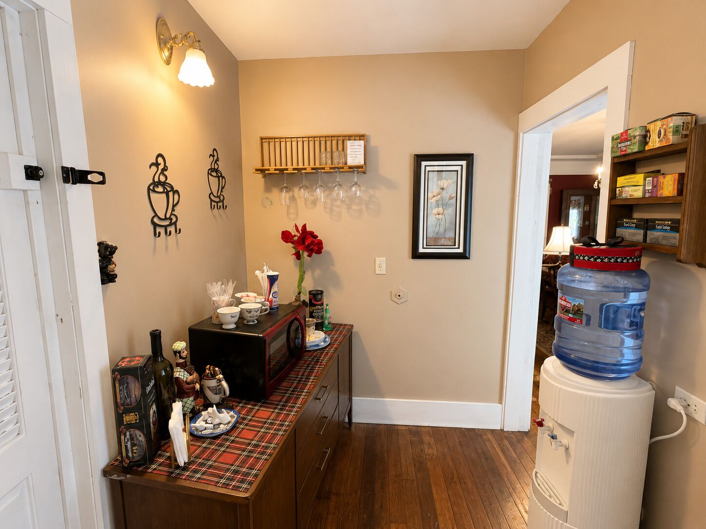 A kitchen with a plaid tablecloth, a water dispenser, and a microwave.