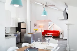Cuina moderna amb armaris blancs, un frigorífic d'acer inoxidable i zona de menjador amb taula blanca preparada per a quatre.