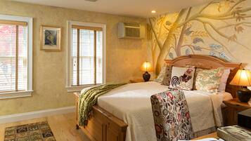 A bedroom with a large bed, two bedside lamps, a window, an air conditioner, and a patterned wall mural.