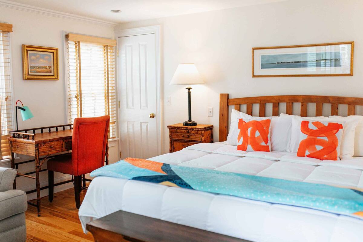 Un dormitorio ordenado con una cama de madera, un escritorio con silla y una lámpara.