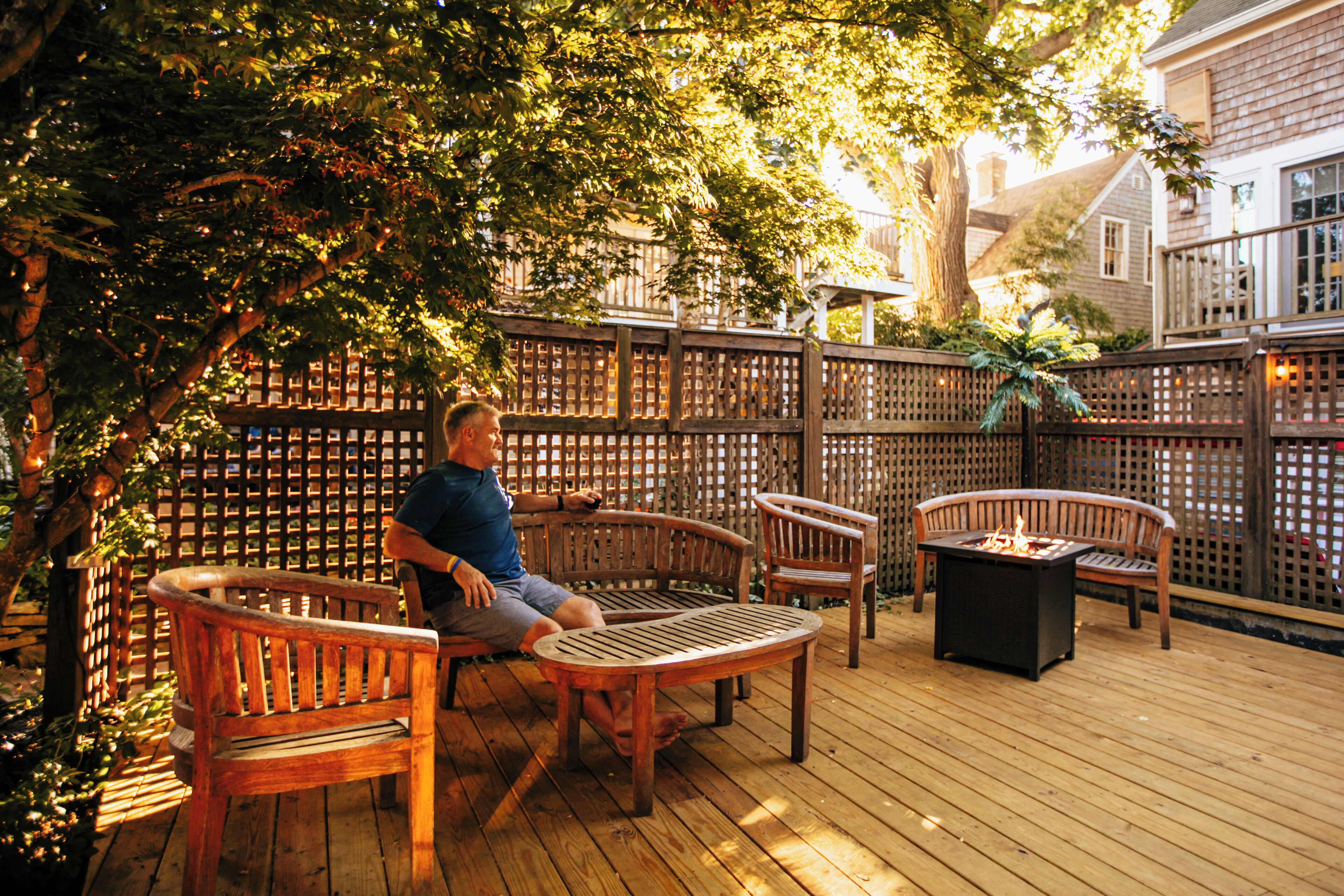 A wooden deck with outdoor furniture, including a bench and chairs, and a fire pit.