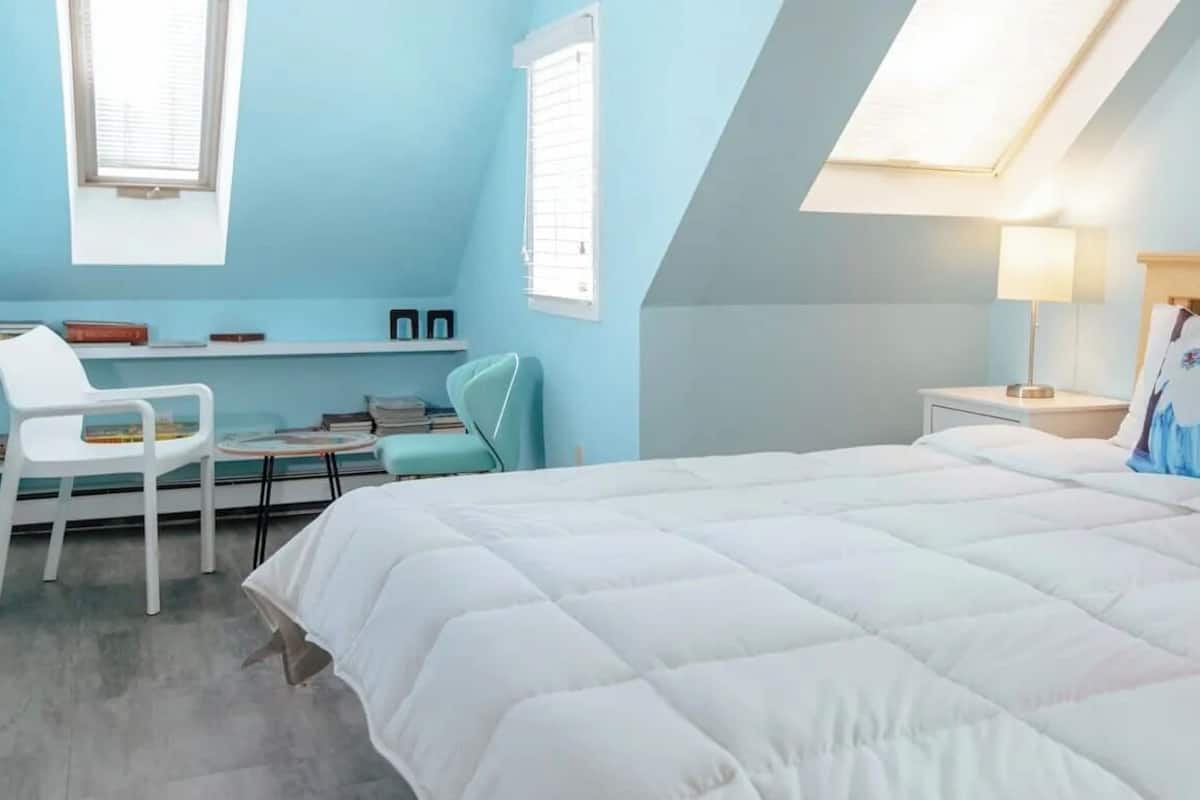 Un dormitorio con cama, escritorio, silla, ventana y lámpara.