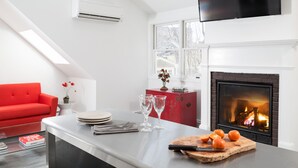 Une cuisine moderne avec une cheminée, un canapé rouge et un coin repas doté d’une table en verre.