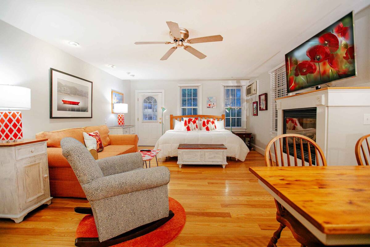 Una habitación bien iluminada con cama, sofá, mesa de comedor y televisor montado en la pared.