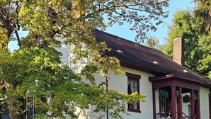 Een huis met een veranda, een schommel en een witte hekwerk.