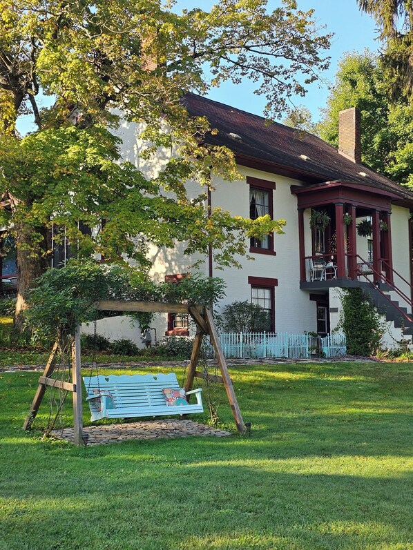 Uma casa com varanda, balanço e cerca branca.