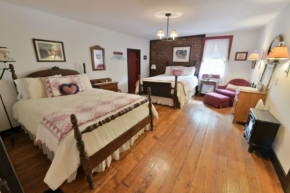 A traditional bedroom with a large bed, a smaller bed, a desk, and a chair.