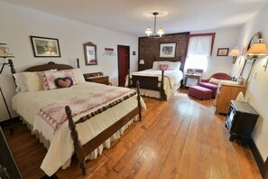 Um quarto tradicional com uma cama grande, uma cama menor, uma escrivaninha e uma cadeira.
