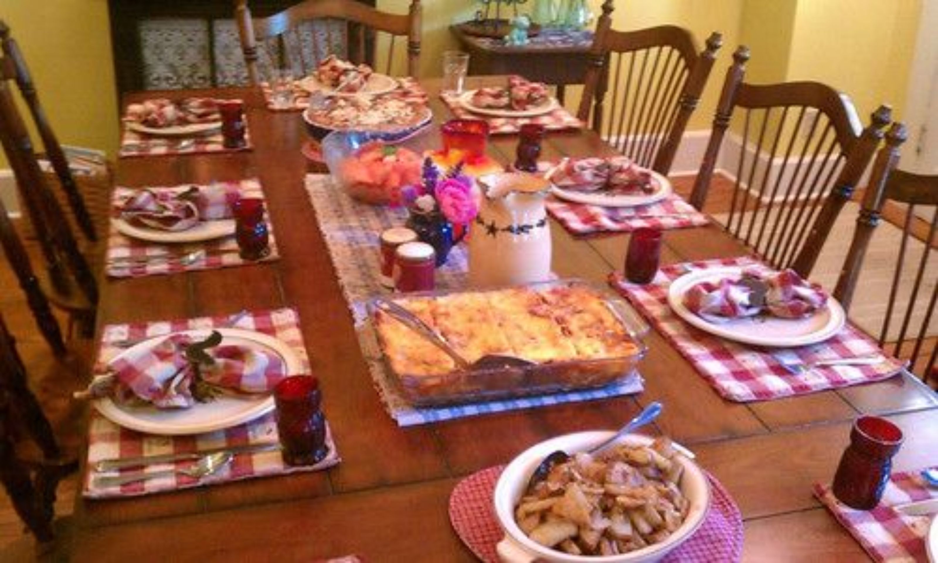 A dining table set with plates, glasses, and a casserole dish.