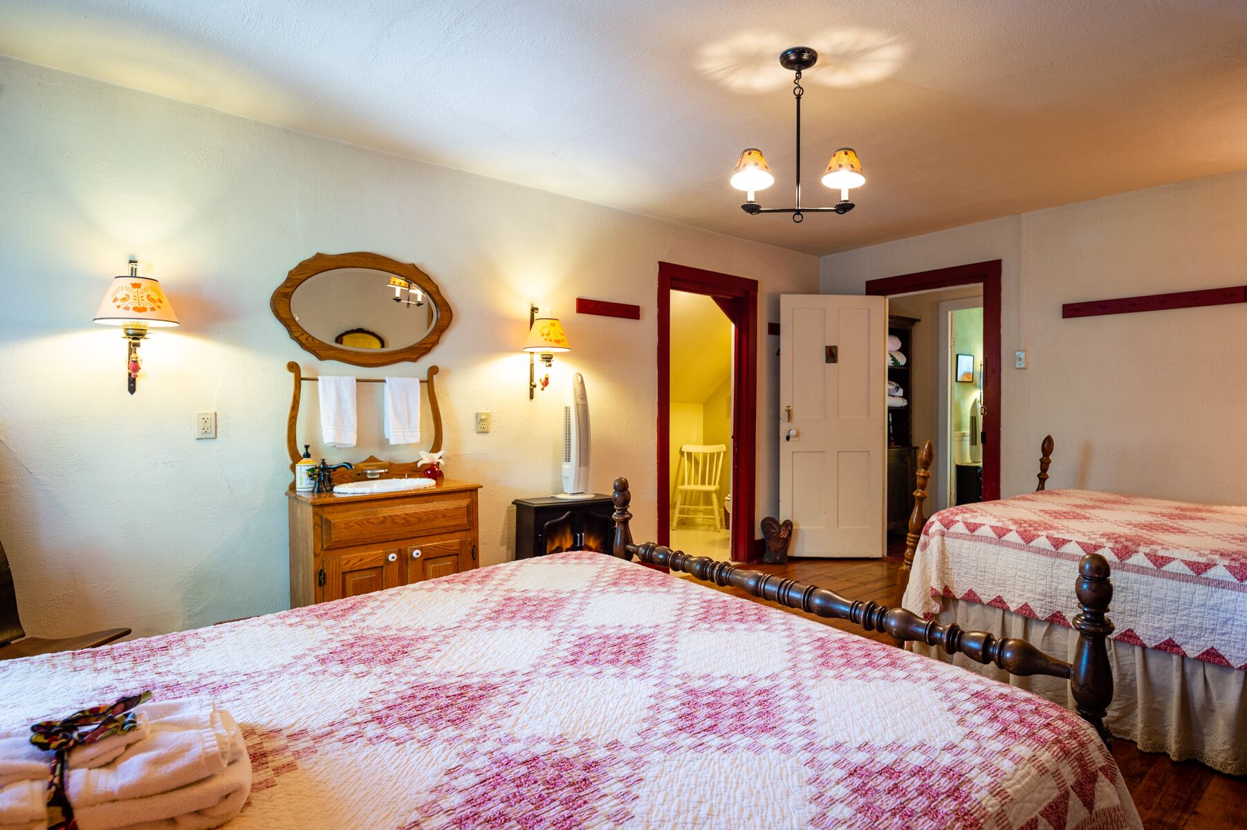 A bedroom with two beds, a wooden dresser, a mirror, and a door leading to another room.