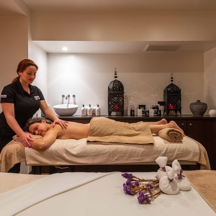 A massage therapy session in a spa room with a massage table, towels, and spa products.