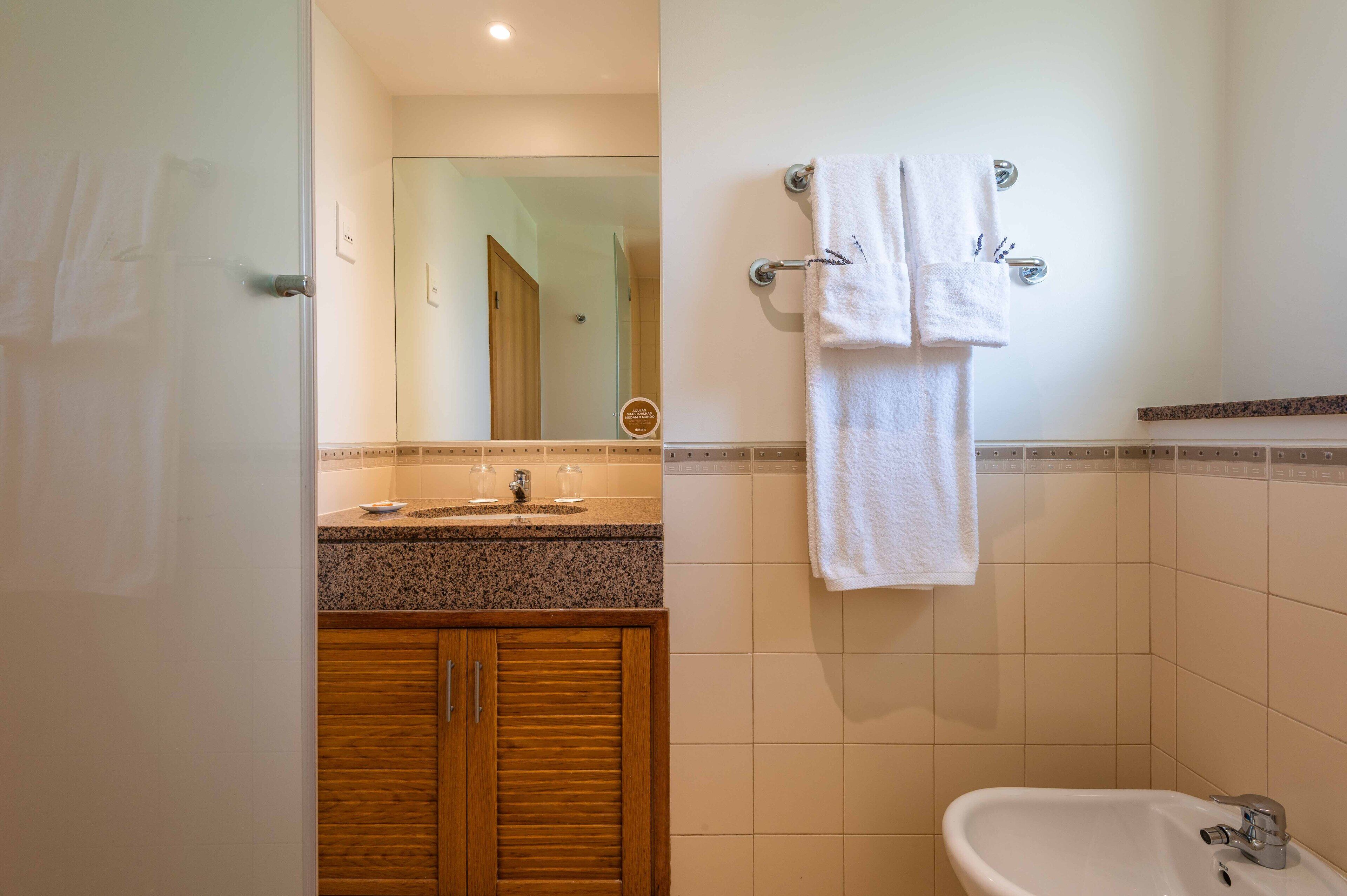 Un baño con lavabo, espejo, toallero y armarios de madera.