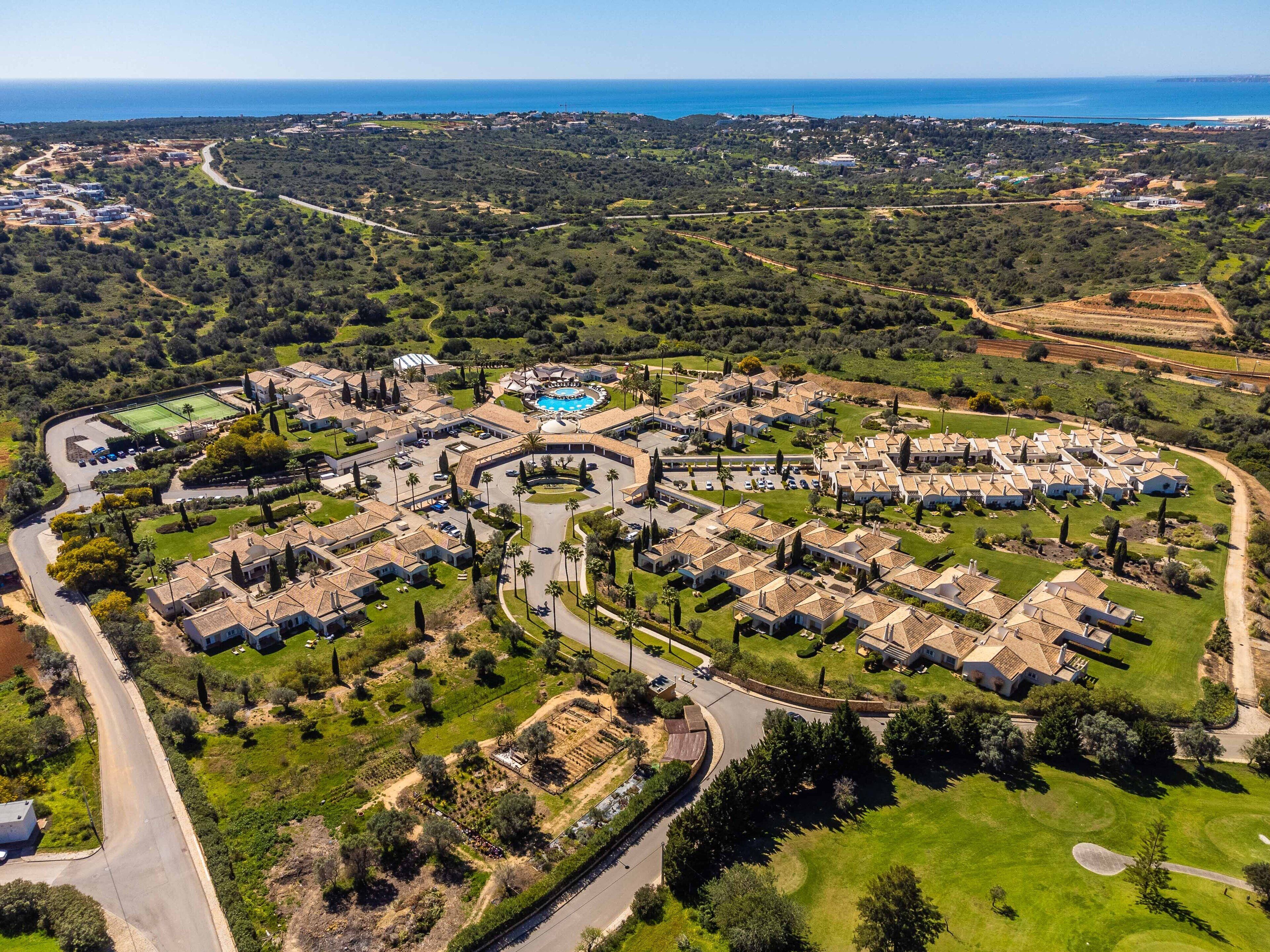 Vue aérienne d’un quartier résidentiel avec des maisons, des rues et une piscine centrale.