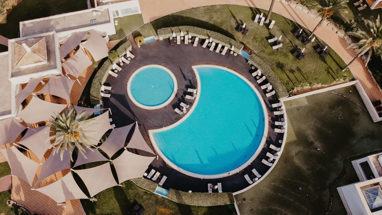 A large circular pool with a smaller inner pool, surrounded by lounge chairs and umbrellas.