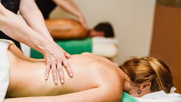 En massageterapeut behandler en klient, som ligger på maven på en massagestol.