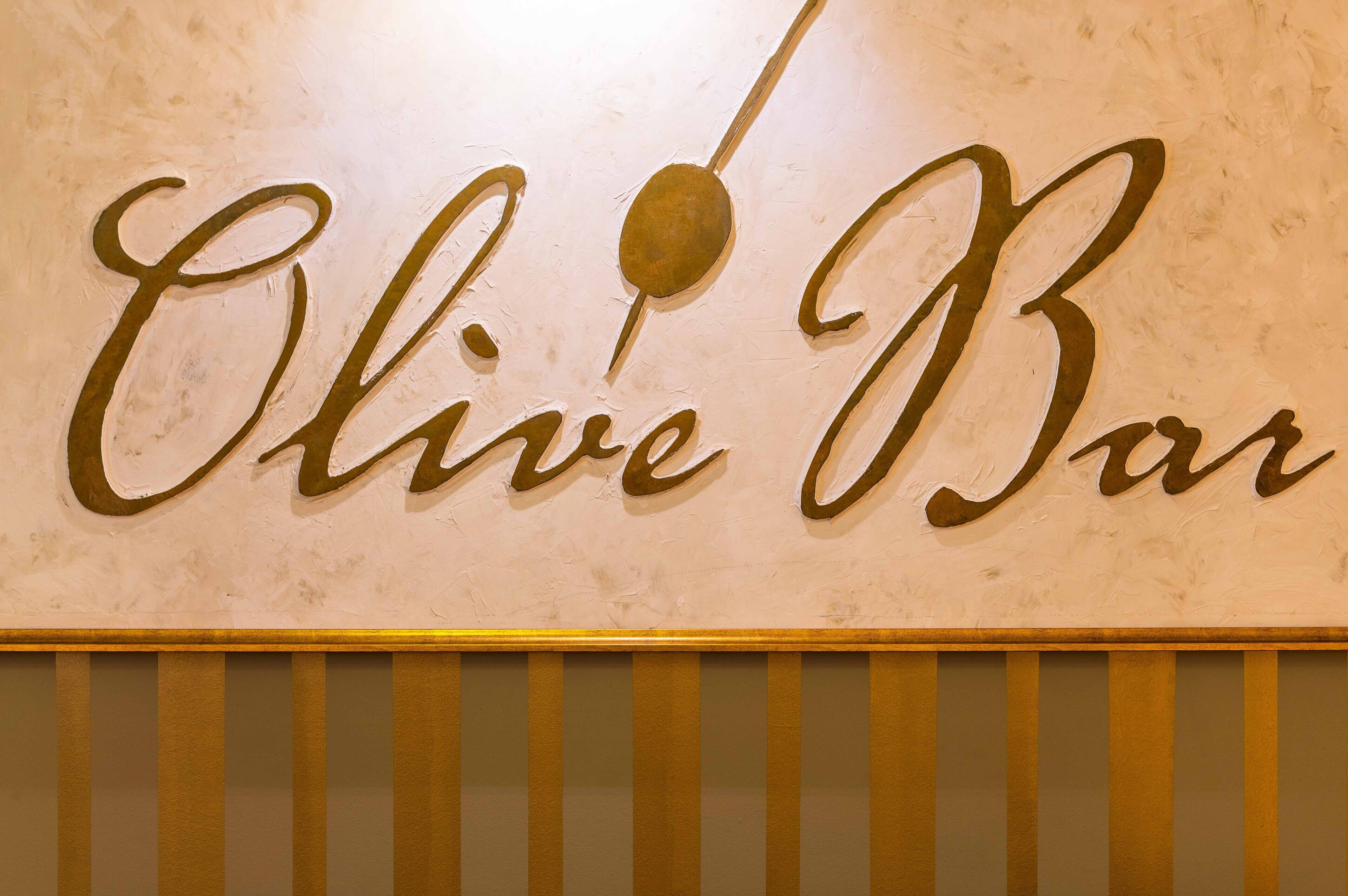 A wall sign with the text "Olive Bar" in a cursive font.