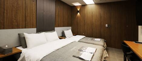 Une chambre d’hôtel avec deux lits, des boiseries, un bureau et une chaise.