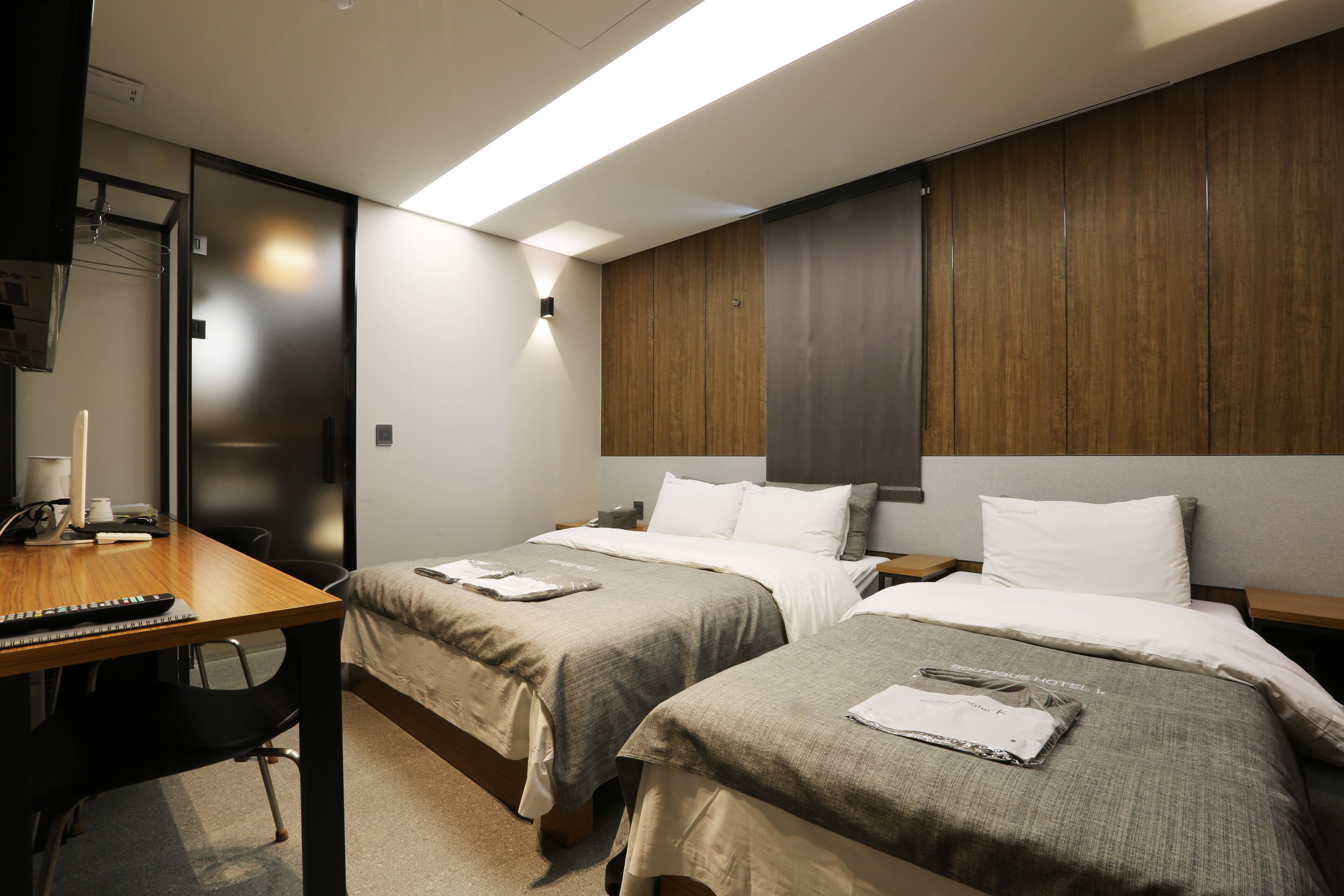 Ett hotellrum med två sängar, ett skrivbord och en stol.