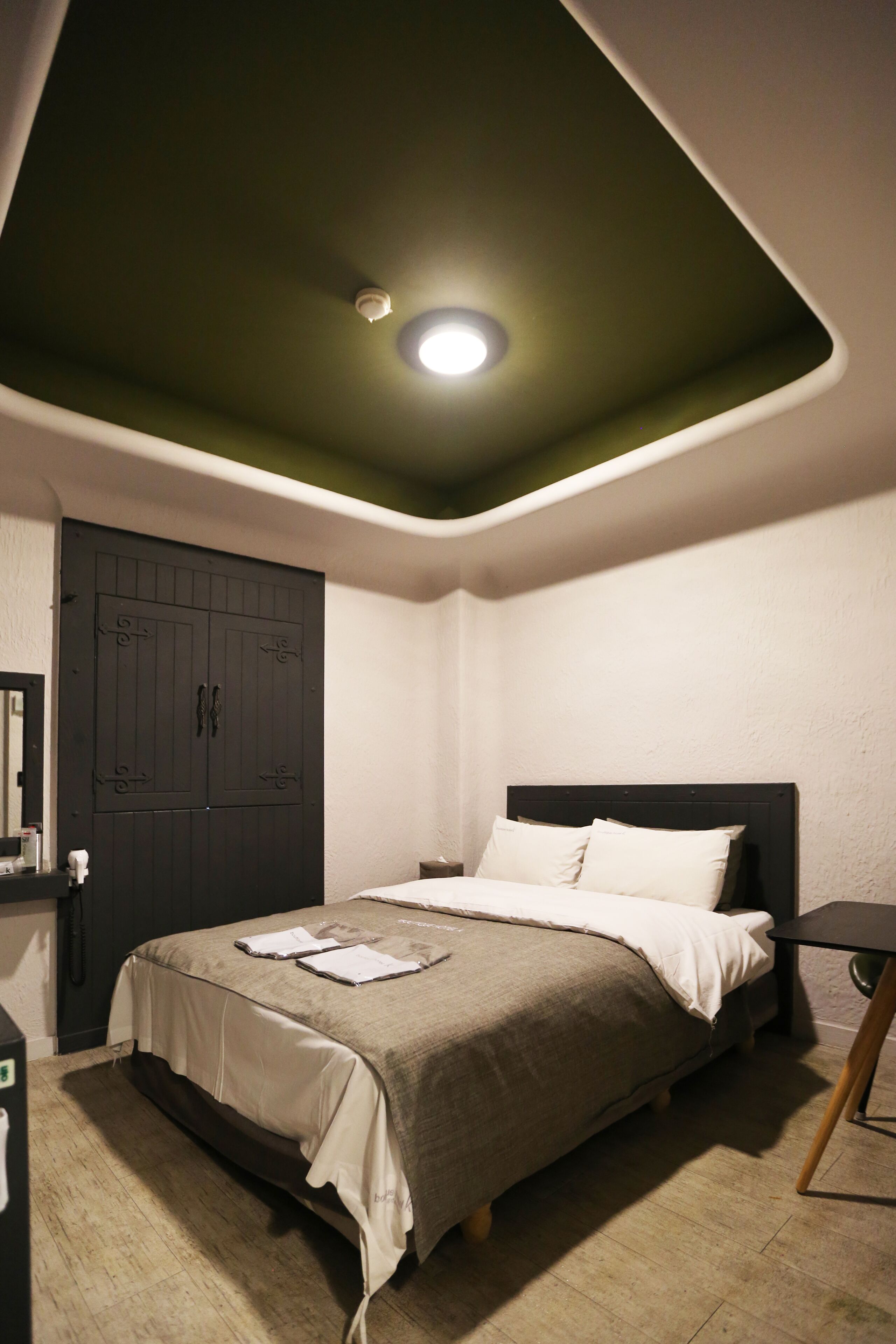 A bedroom with a bed, a wardrobe, and a ceiling light.