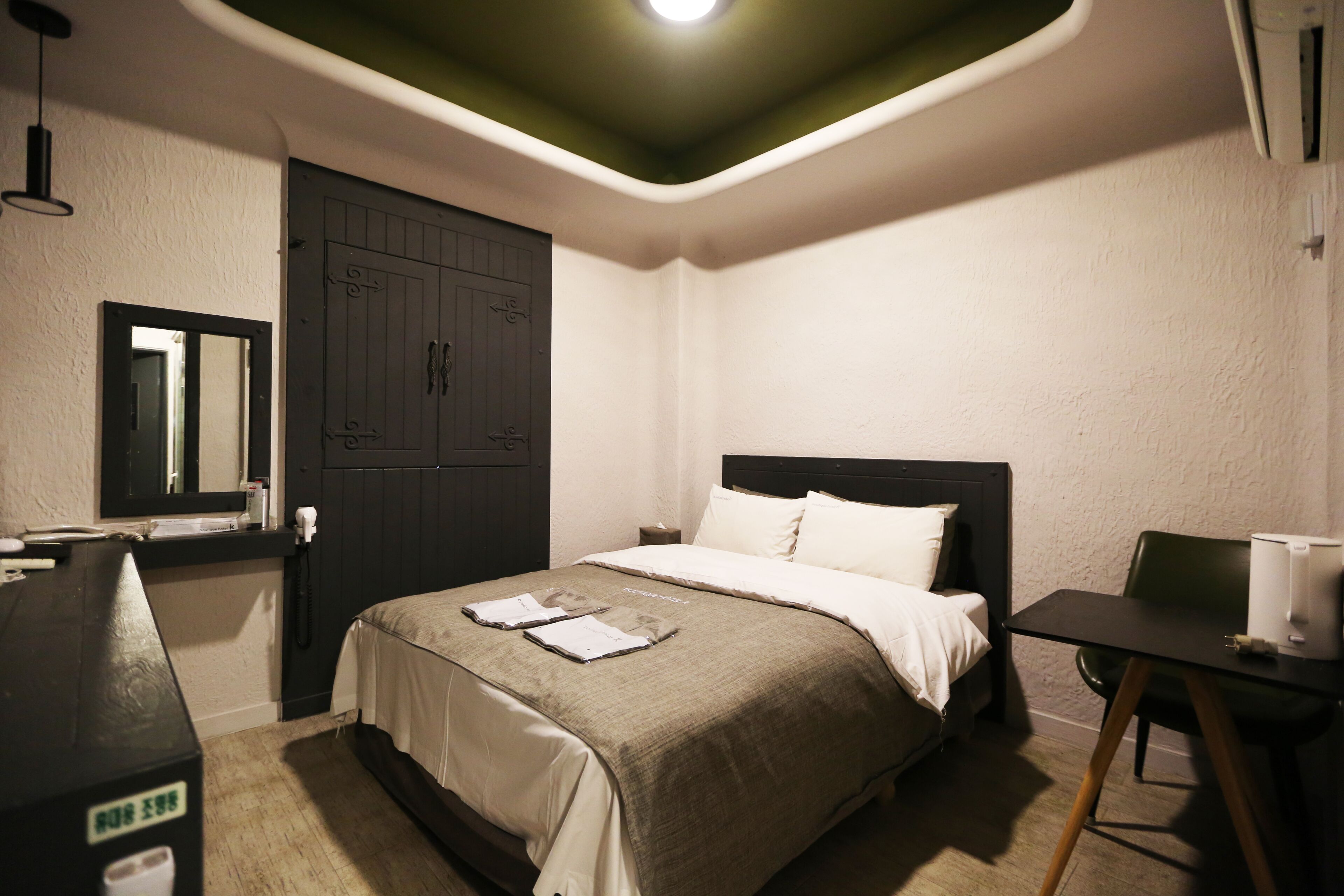 A hotel room with a bed, bedside table, desk, and a wardrobe.