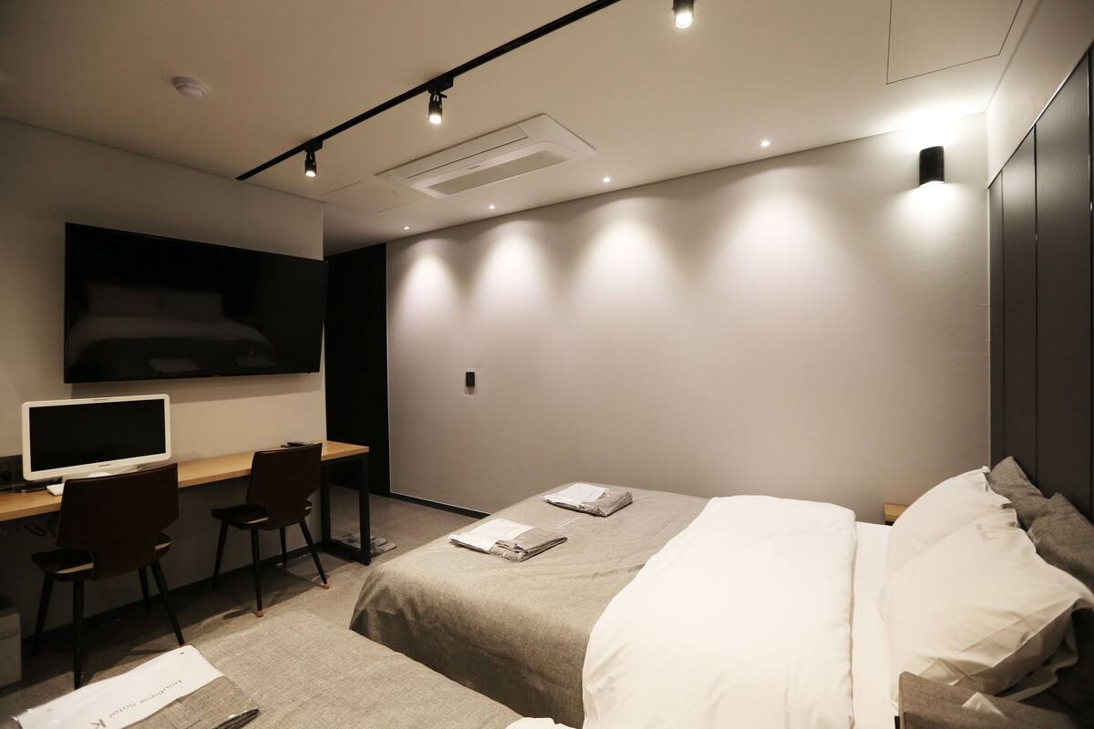 Una habitación de hotel moderna con una cama, un escritorio con computadora y un televisor.