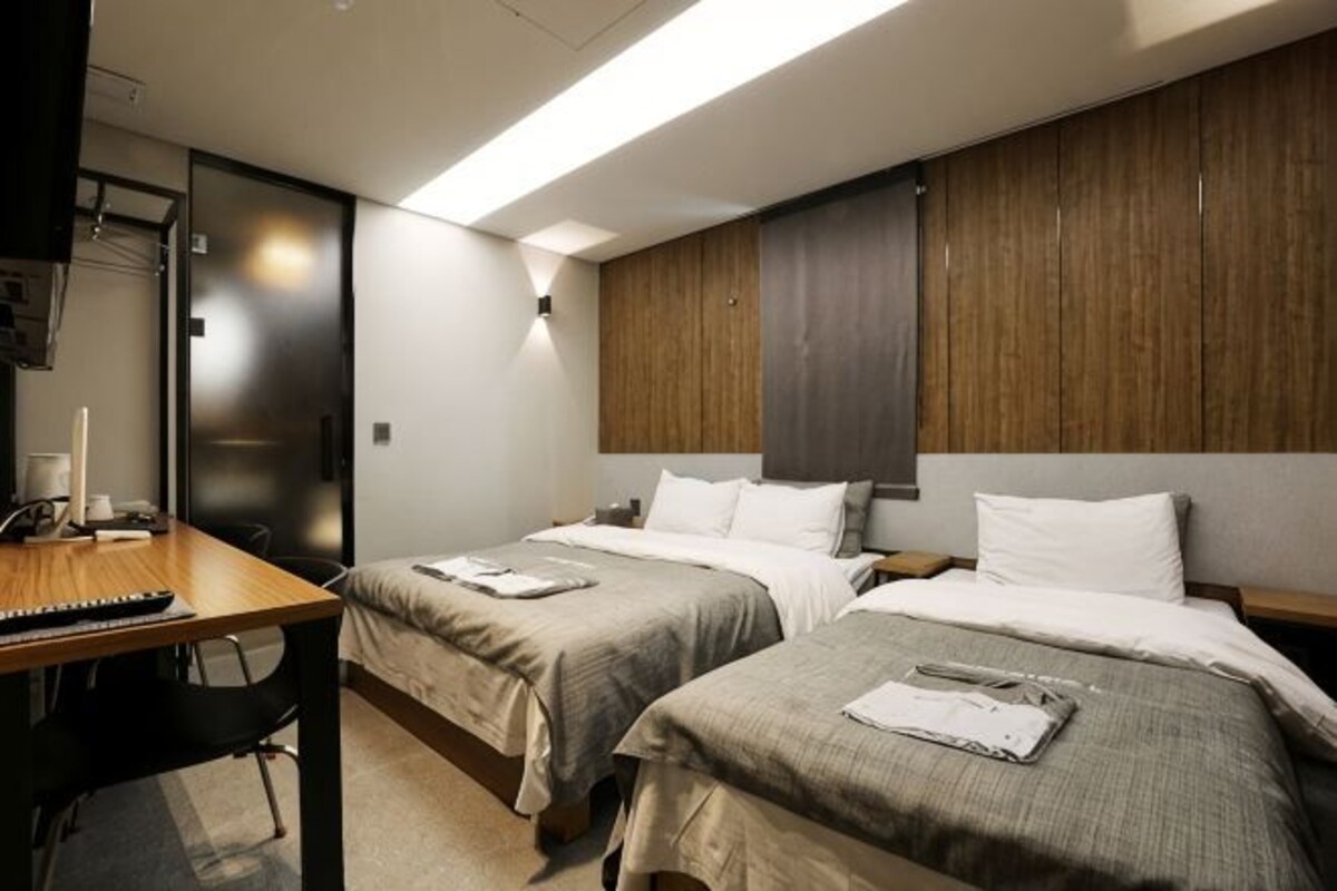 Een hotelkamer met twee bedden, een bureau en een kledingkast.