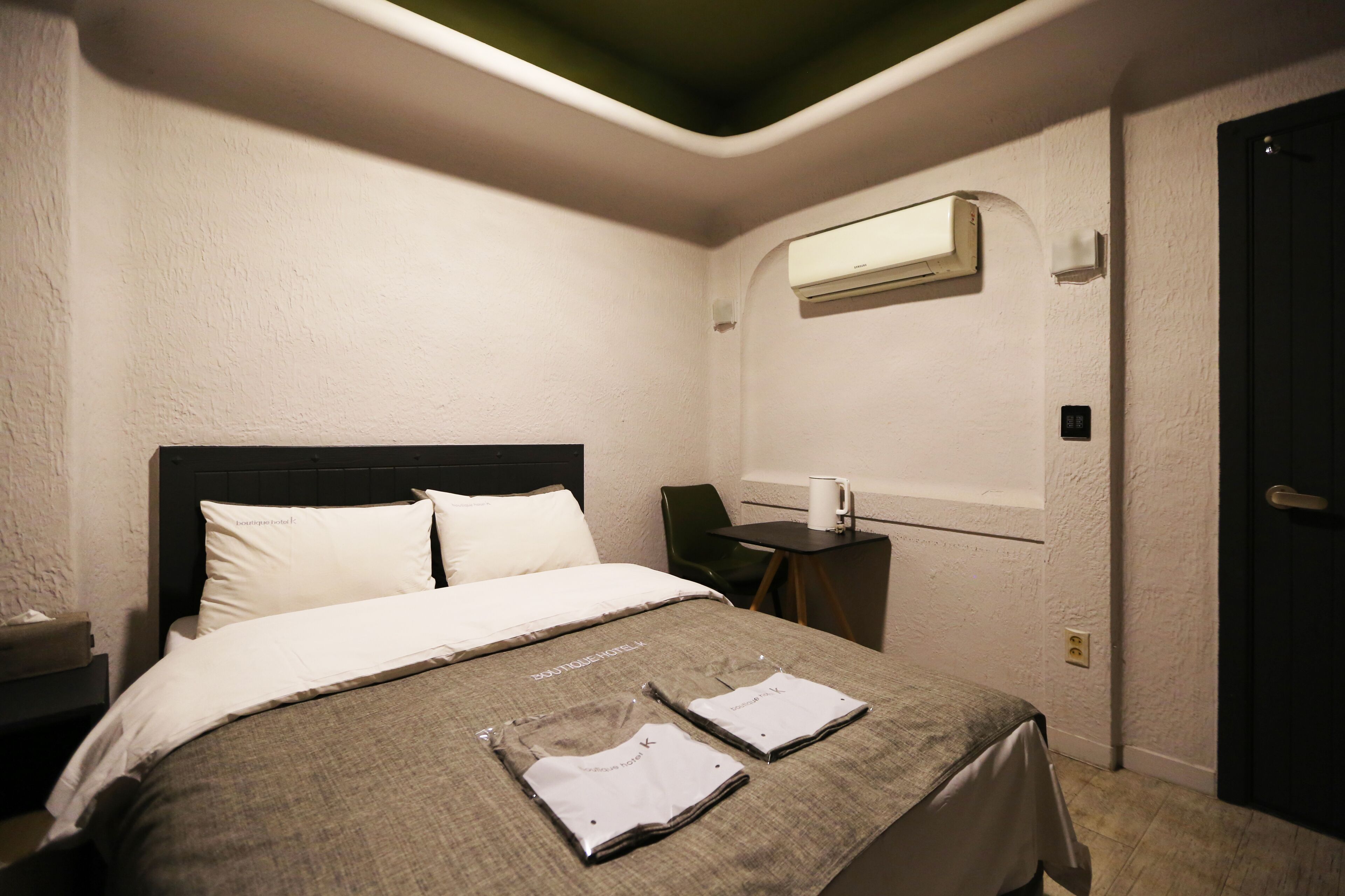 Quarto de hotel com cama, escrivaninha, cadeira e ar condicionado.