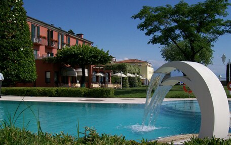 A swimming pool with a water feature, surrounded by buildings and greenery.