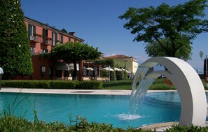 A swimming pool with a water feature, surrounded by buildings and greenery.