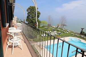 A balcony with a pool, lounge chairs, and a view of the lake.